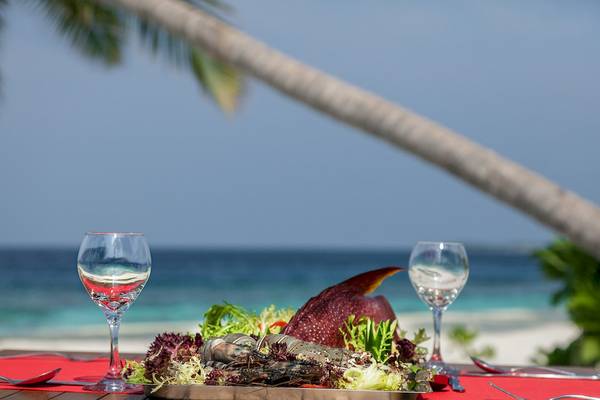 Tisch mit Hummergericht und Weingläsern mit Blick auf das Meer im Reethi Faru Resort.