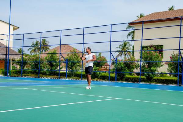 Tennisplatz im Reethi Faru Resort mit einem Mann, der bereit ist zu spielen.