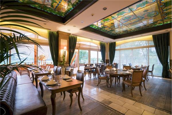 Innenansicht des Restaurants im Voyage Belek Golf & Spa Hotel mit runden Tischen und Stühlen.