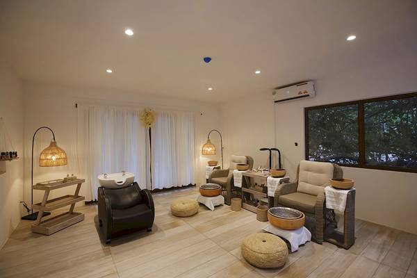 Spa-Bereich im Reethi Faru Resort mit Holzboden, weißen Vorhängen und bequemen Sesseln.