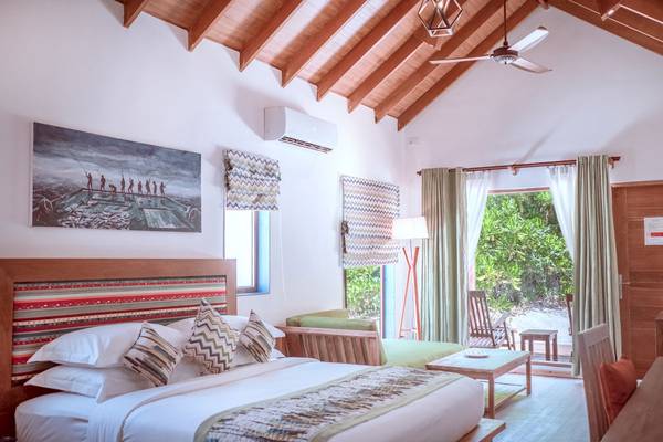Schlafzimmer im Reethi Faru Resort mit einem großen Bett, Deckenventilator und Klimaanlage.