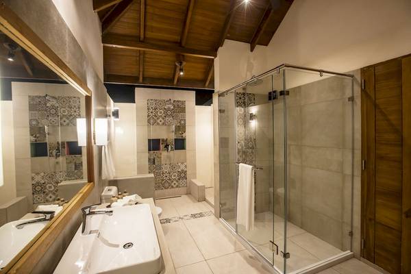 Badezimmer im Reethi Faru Resort mit Glasdusche, Waschbecken und bemalten Wänden.