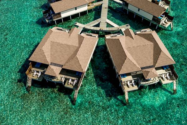 Luftaufnahme des Reethi Faru Resorts mit Wasservillen im Meer