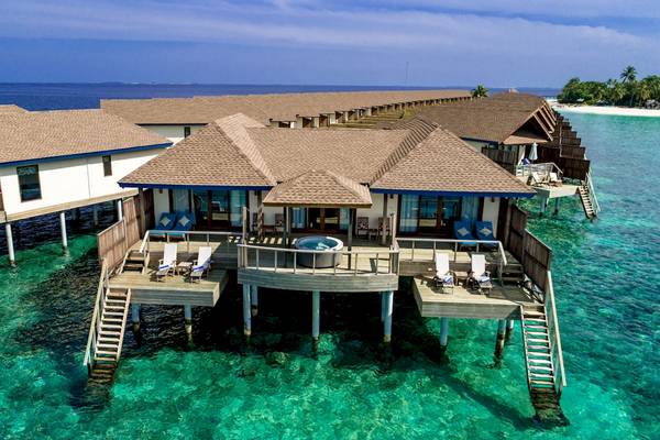 Luftaufnahme des Reethi Faru Resorts mit mehreren Wasservillen am Meer