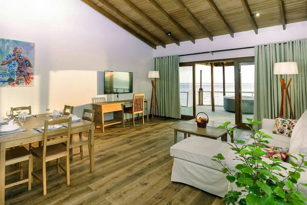 Wohnbereich im Reethi Faru Resort mit Blick auf das Meer und einem Whirlpool auf der Terrasse.