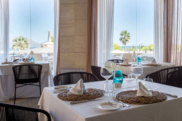 Innenansicht des Restaurants des Sarena de Muro Resort Mallorca mit Tischen und Blick auf den Ozean.