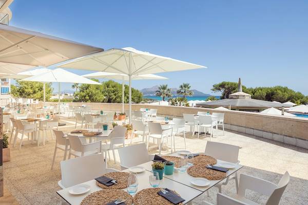 Terrasse des Sarena de Muro Resorts auf Mallorca mit Tischen, Stühlen und Sonnenschirmen
