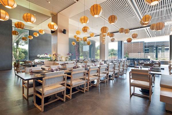 Innenansicht des Restaurants im Voyage Belek Golf & Spa mit hängenden Laternen und gedeckten Tischen.