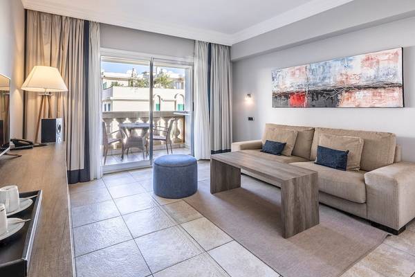 Wohnbereich des Sarena de Muro Resort Mallorca Hotels mit einem Sofa, einem Tisch und einem Balkon.