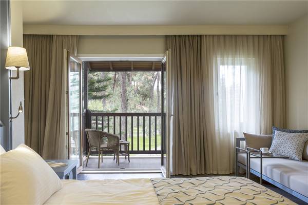 Schlafzimmer im Voyage Sorgun Hotel mit offenem Balkon und Blick auf einen Garten.