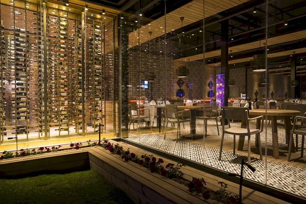 Innenansicht des Voyage Sorgun Hotels mit gespiegelten Wänden, Weinregal und Tisch- und Stuhlanordnung.