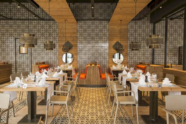Innenbereich des Voyage Sorgun Restaurants mit gemusterten Wänden, Holztischen und modernen Lampen.