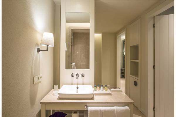 Badezimmer im Voyage Sorgun Hotel mit Waschbecken, Spiegel und Toilettenartikeln.