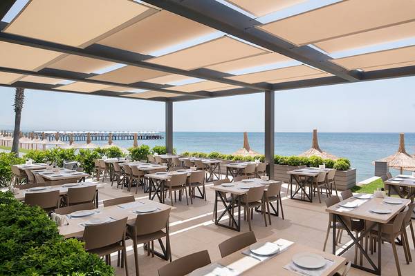 Außenterrasse des Voyage Sorgun Hotels mit Blick auf das Meer und eine lange Promenade.