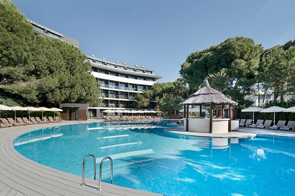 Außenpool des Voyage Belek Golf & Spa Hotels mit Sonnenliegen und Schirmen