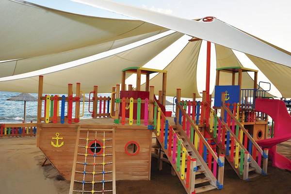 Kinderspielplatz am Strand im Voyage Sorgun Hotel mit bunten Kletterelementen und Rutsche.