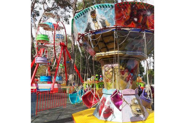 Ein buntes Karussell und eine Achterbahn im Freizeitpark Voyage Sorgun.