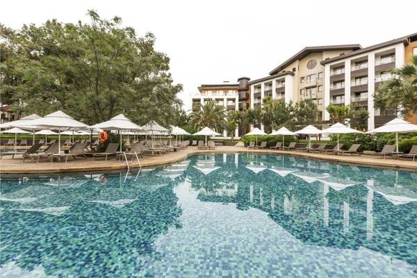 Außenpool des Voyage Sorgun Hotels mit Sonnenliegen und weißen Sonnenschirmen.