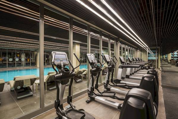 Fitnessstudio im Voyage Sorgun Hotel mit Laufbändern und Blick auf den Pool.