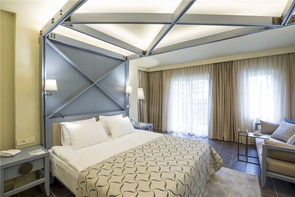 Innenansicht eines eleganten Hotelzimmers im Voyage Sorgun Hotel mit einem großen Bett, Lampen und einem Ausblick auf die Fenster.
