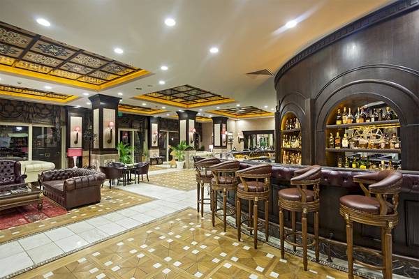 Lobby-Bar des Voyage Belek Golf & Spa Hotels mit gepolsterten Stühlen und einer Bar im Hintergrund.