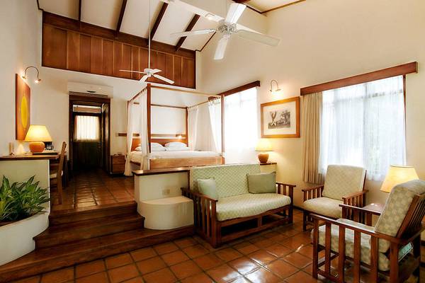 Hotelzimmer im Capitan Suizo Beachfront Boutique Hotel mit Bett, Sofa, Stühlen und Klimaanlage.