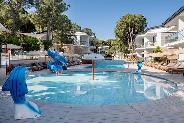 Außenpoolbereich des Voyage Belek Golf & Spa mit blauen Wasserrutschen und Sonnenliegen.
