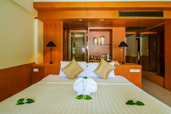 Ein Doppelbett im Seaview Patong Hotel Zimmer mit dekorativen Blättern und zwei Kissen.