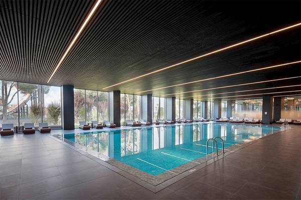 Innenpool des Voyage Belek Golf & Spa Hotels mit Loungebereich und geschwungenen Lichtleisten