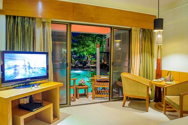 Hotelzimmer mit Fernseher, Tisch, Stühlen und Poolaussicht durch Glastüren