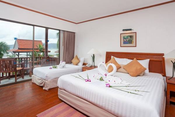 Hotelzimmer im Seaview Patong mit zwei Betten, Meerblick und Dekor mit Schwänen und Blumen.