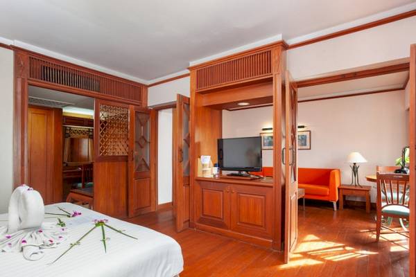 Innenansicht eines Zimmers im Seaview Patong Hotel mit Doppelbett, Fernseher und Couch.