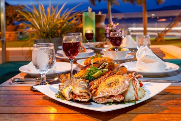 Ein Abendessen am Tisch im Seaview Patong mit Fisch und Krebsen, Wein und Wassergläsern.