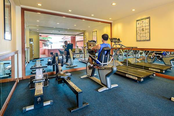 Fitnessraum im Seaview Patong Hotel mit verschiedenen Trainingsgeräten und einem Mann auf einem Fahrrad