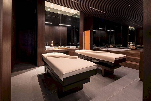 Massageraum im Voyage Belek Golf & Spa Hotel mit zwei Behandlungstischen und Waschbecken.