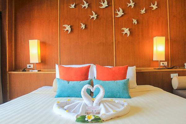 Zimmer im Seaview Patong Hotel mit einem Bett, zwei weißen Handtüchern in Form von Schwänen und einem weißen Flieder auf dem Bett.