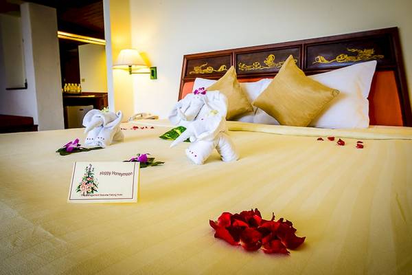 Foto eines Hotelzimmers mit Flieder und Rosen auf dem Bett für Flitterwochen.