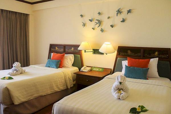 Zwei Betten mit blauen und orangefarbenen Kissen im Seaview Patong Hotelzimmer.