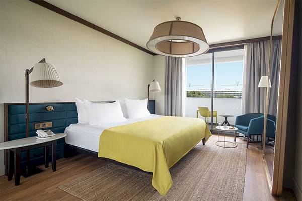 Voyage Belek Golf & Spa Hotelzimmer mit Bett, Lampen, Tisch und Blick auf die Landschaft.