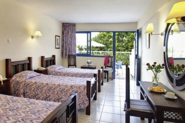 Ein Zimmer im Bella Napa Bay Hotel mit vier Betten, einem Tisch, einem Spiegel und einer Terrasse.