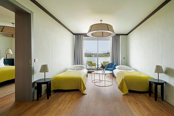 Doppelzimmer im Voyage Belek Golf & Spa mit Zusatzbetten und Blick auf den Golfplatz.