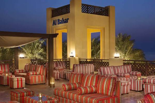 Loungebereich des Hilton Ras Al Khaimah Beach Resort bei Nacht mit roten und weißen Stühlen und Lampen.