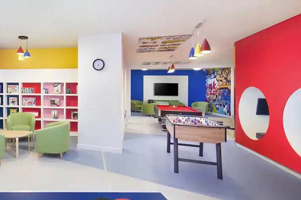 Das farbenfrohe Kinderzimmer des Hilton Ras Al Khaimah Beach Resort mit Bücherregalen, Tischen, Stühlen und Spielen.