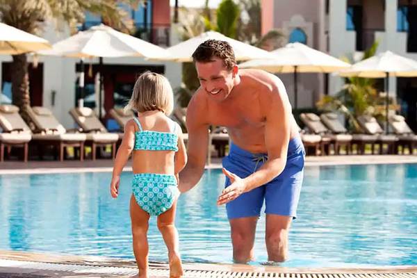 Mann und Kind im Schwimmbad des Hilton Ras Al Khaimah Beach Resort