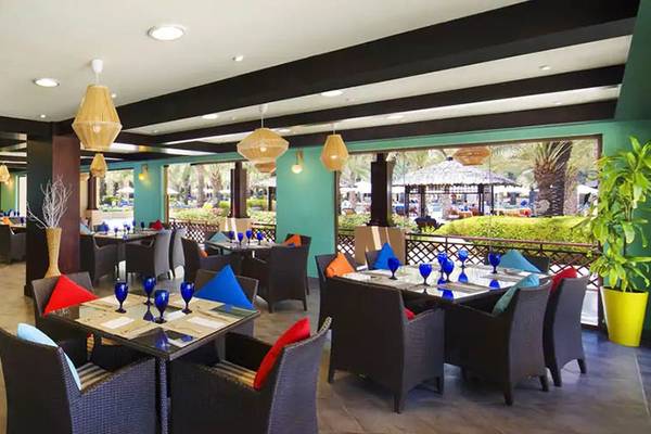 Innenansicht des Restaurants im Hilton Ras Al Khaimah Beach Resort mit farbenfrohen Tischen und Stühlen.