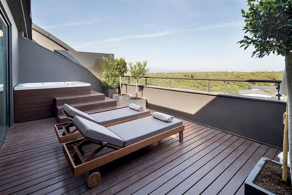 Terrasse des Voyage Belek Golf & Spa mit zwei Liegen, Jacuzzi und Blick auf eine Landschaft.