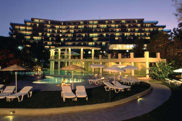 Abendliche Ansicht des Calypso Beach Hotels mit illuminierten Fenstern und Außenbereich mit Pool und Liegestühlen.