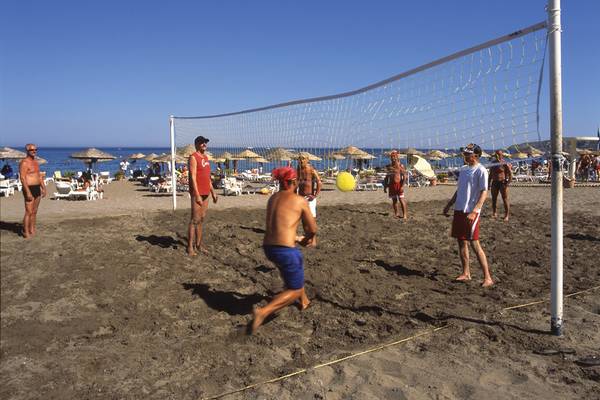 Gruppe von Männern spielt Volleyball auf dem Strand des Calypso Beach Hotels.