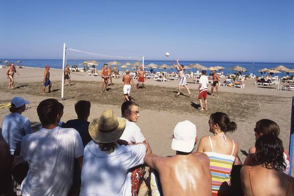 Volleyballspiel am Strand mit Zuschauern, Hotelname Calypso Beach im Hintergrund.