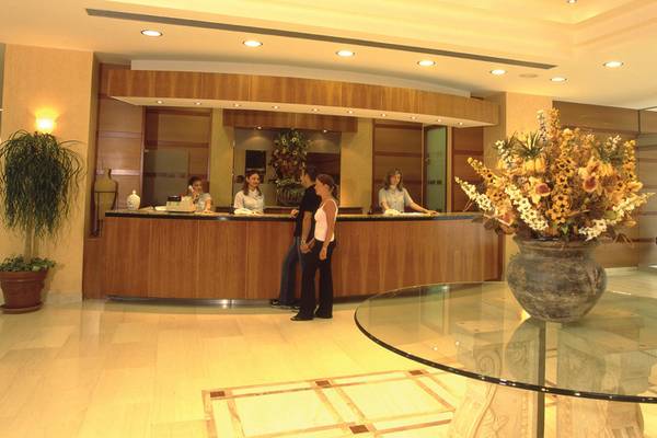 Receptionsbereich im Calypso Beach Hotel mit drei Angestellten und zwei Gästen.